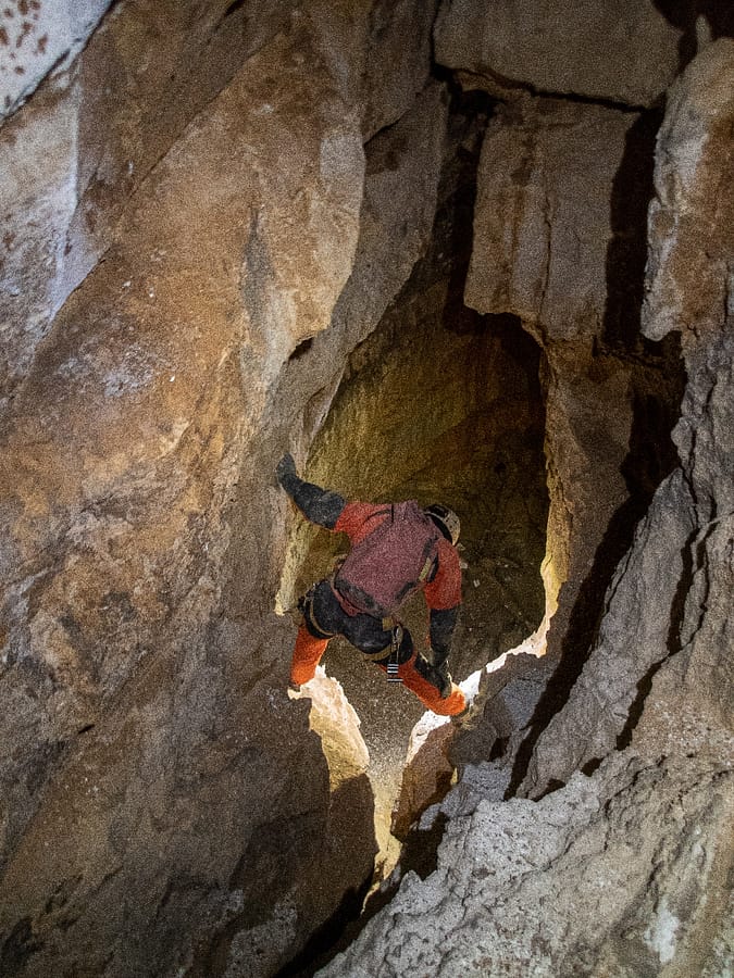 A caver assesses the depth and potential of the pit that leads further into the cave and farther from the surface. Photo: Katarina Kosič Ficco